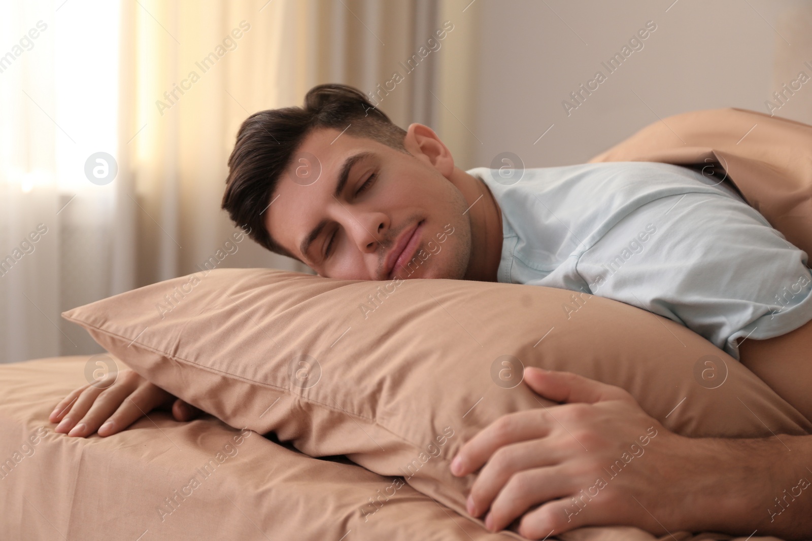 Photo of Man sleeping in bed with brown linens at home