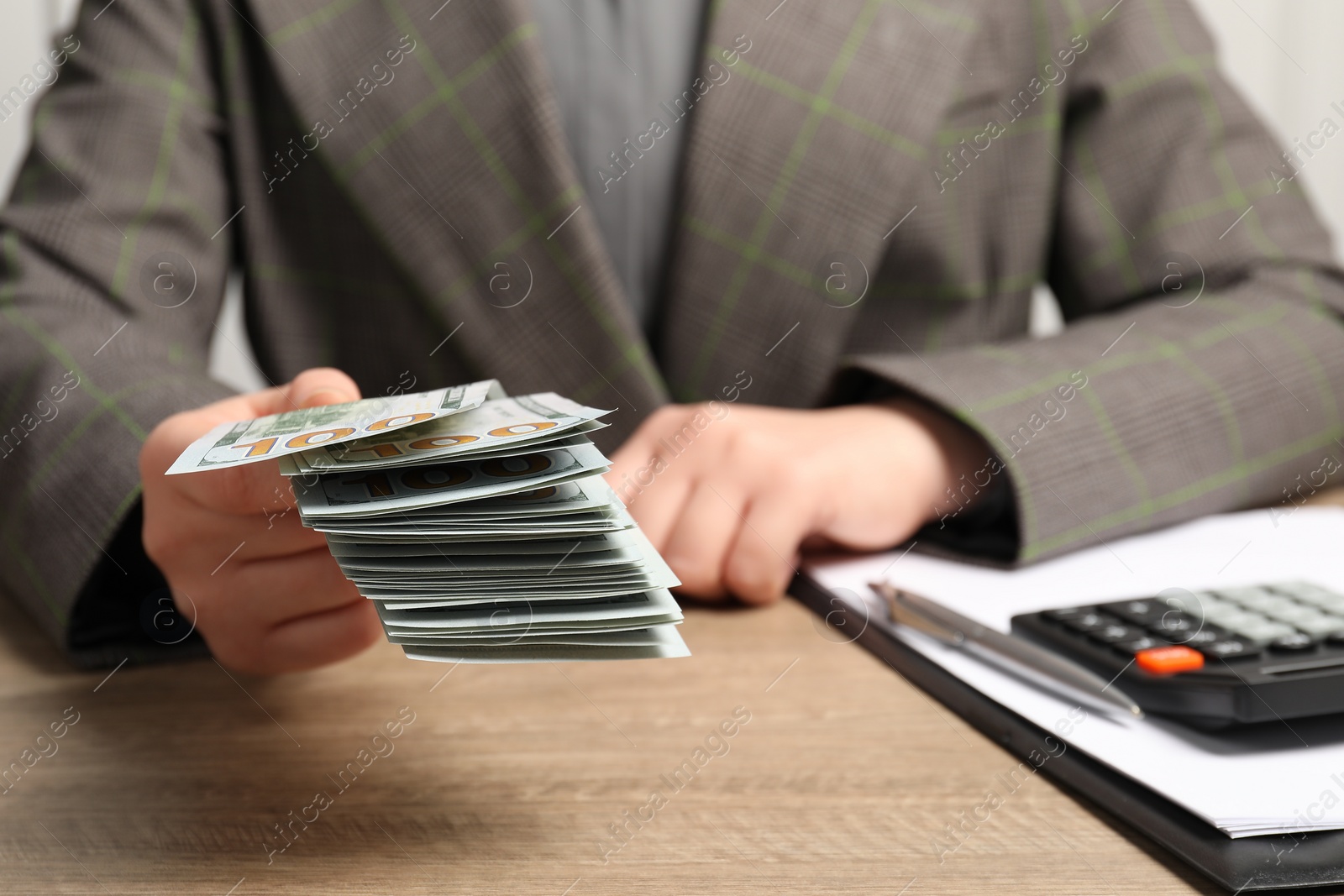 Photo of Money exchange. Woman holding dollar banknotes at wooden table, closeup