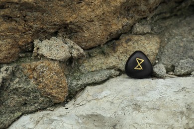Photo of Black rune Dagaz on stone outdoors. Old Germanic alphabet
