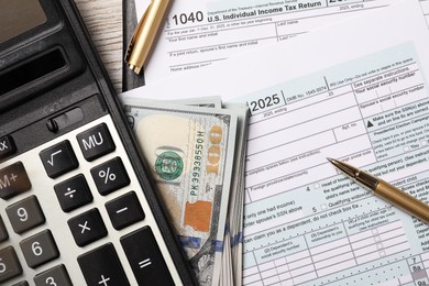 Tax return forms, dollar banknotes, calculator and pen on table, flat lay