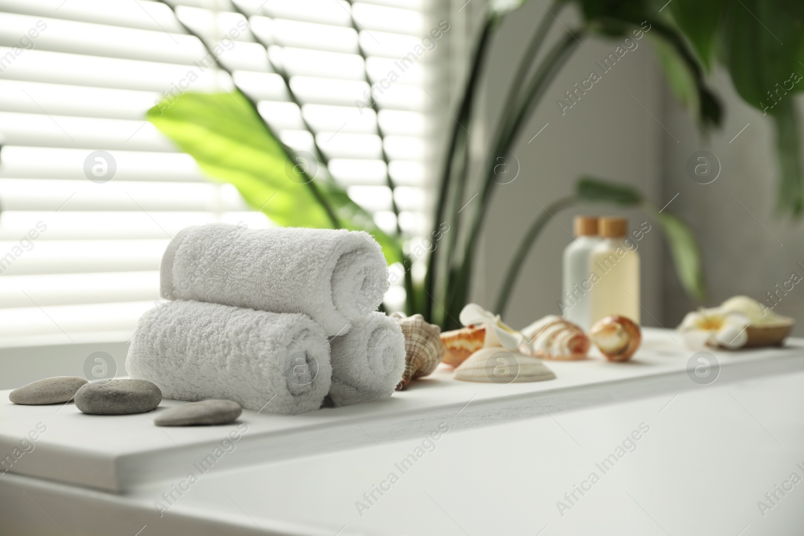 Photo of Bath tray with spa products and towels on tub in bathroom