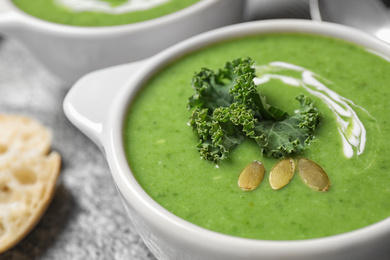 Tasty kale soup with pumpkin seeds on grey table, closeup