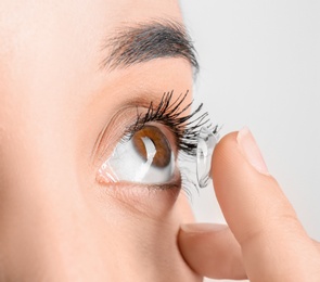 Photo of Young woman putting contact lens in her eye, closeup