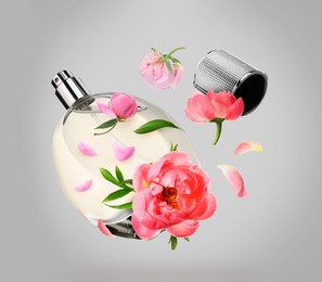 Bottle of perfume and peonies in air on grey background. Flower fragrance