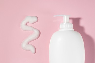 Photo of Dispenser with cleansing foam on pink background, flat lay. Cosmetic product