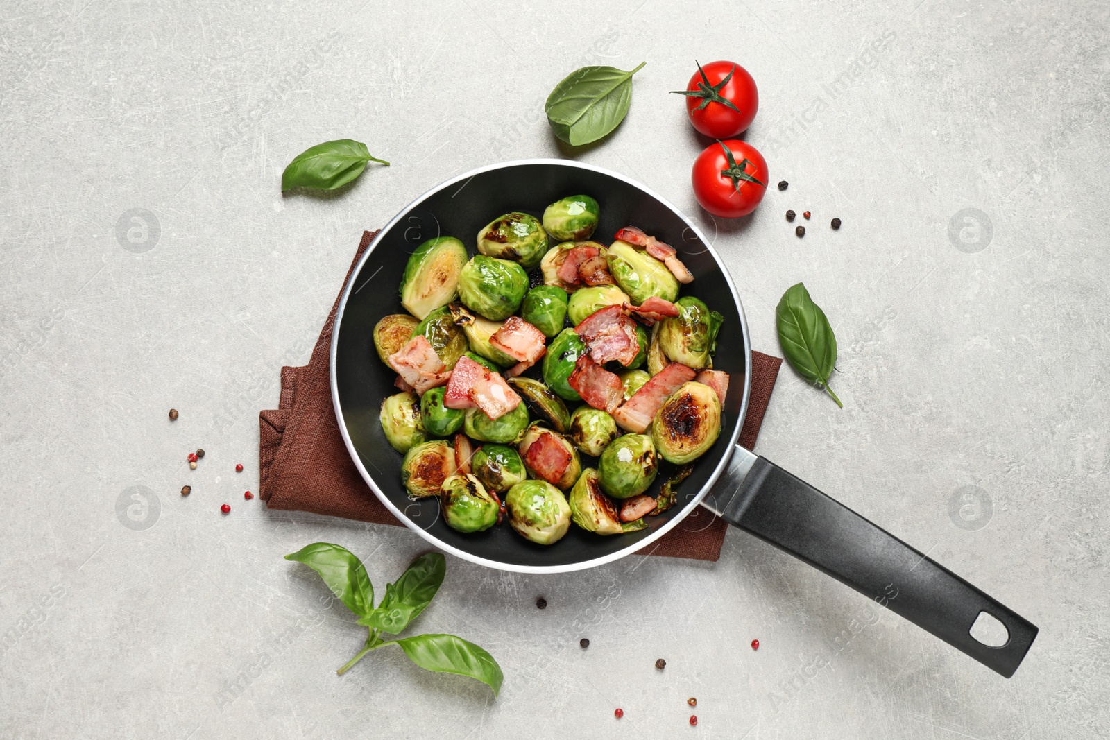 Photo of Delicious Brussels sprouts with bacon in pan on light table, flat lay