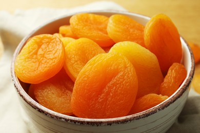 Photo of Bowl of tasty apricots on table, closeup. Dried fruits