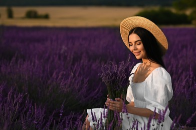 Photo of Beautiful young woman with bouquet sitting in lavender field