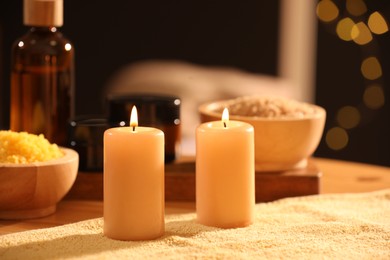 Spa composition with burning candles and personal care products on soft light surface, closeup