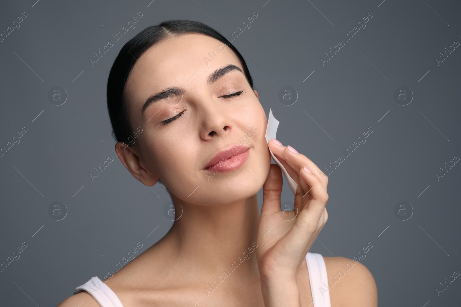 Photo of Beautiful woman using mattifying wipe on grey background