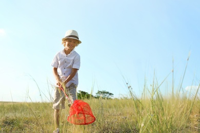 Cute little boy with butterfly net outdoors, space for text. Child spending time in nature