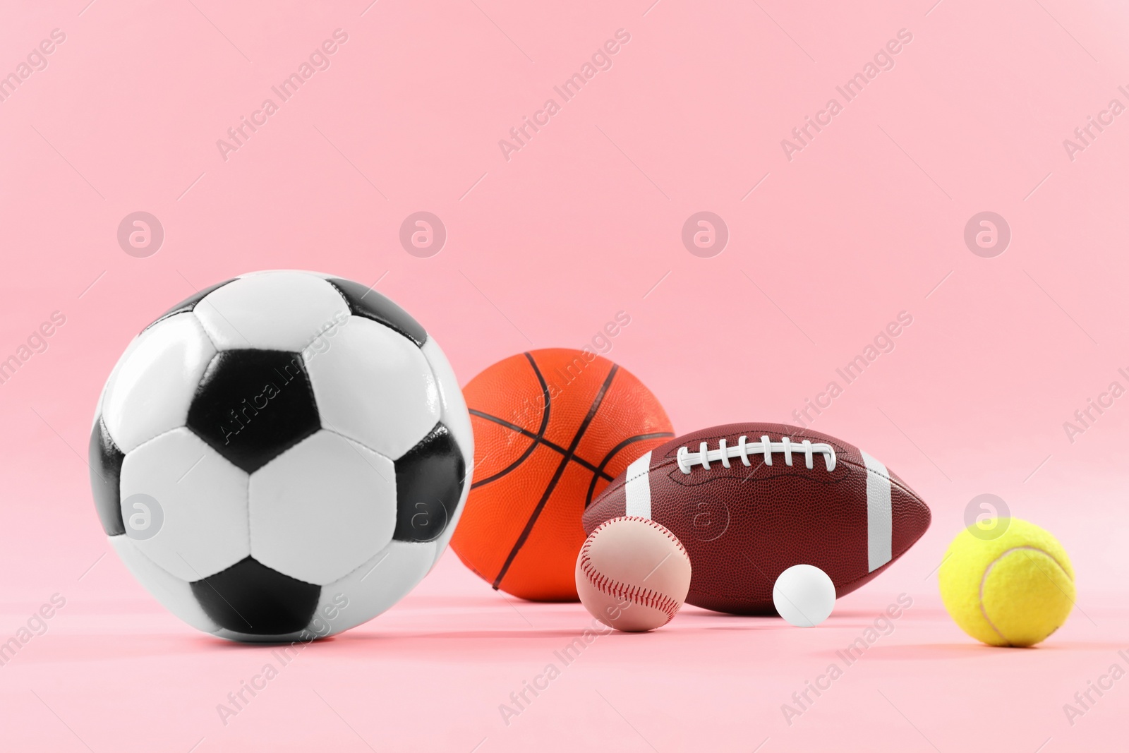 Photo of Many different sports balls on pink background, space for text