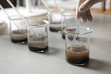 Scientist preparing soil extract at table, closeup. Laboratory analysis