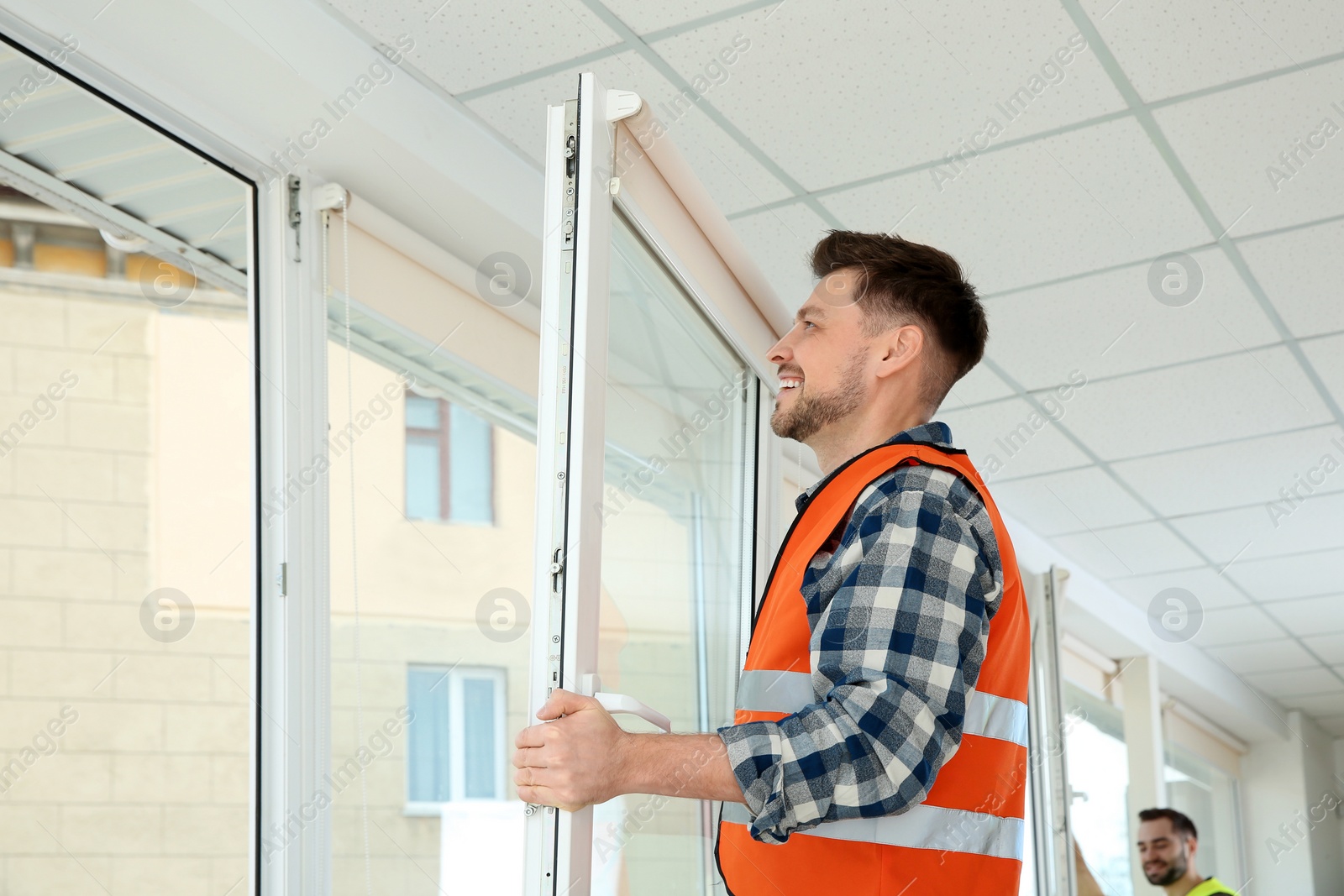 Photo of Construction worker installing plastic window in house