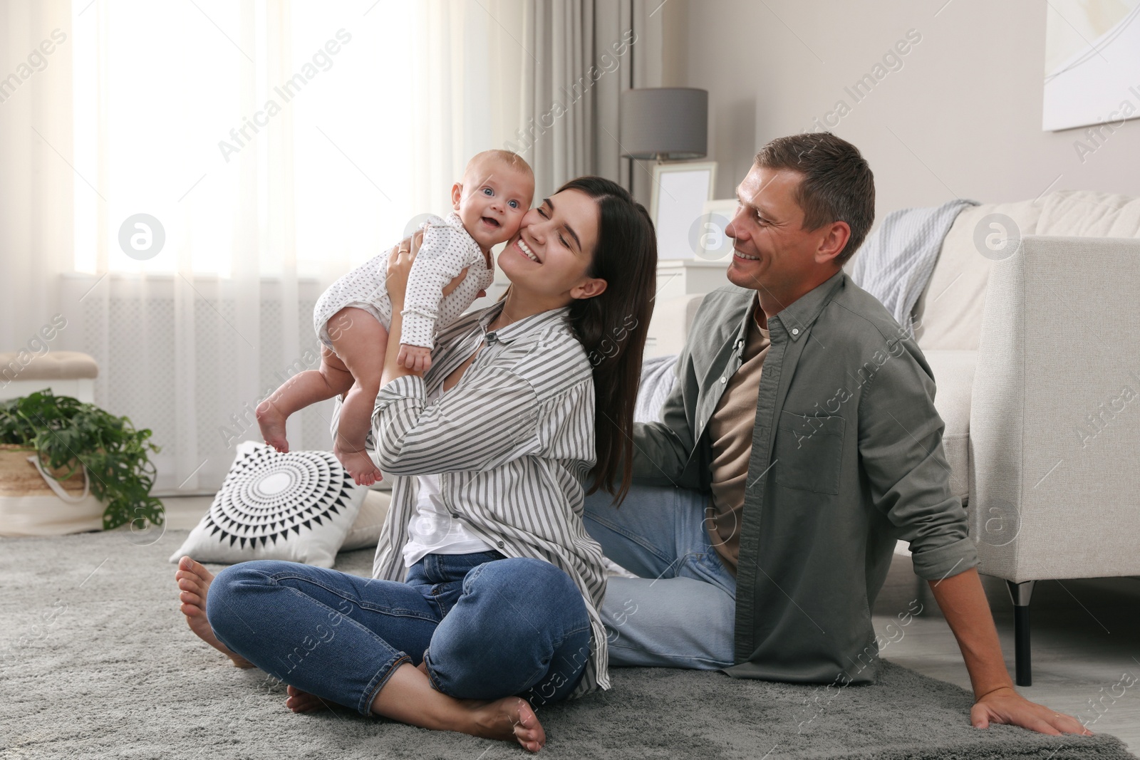 Photo of Happy family with their cute baby on floor in living room