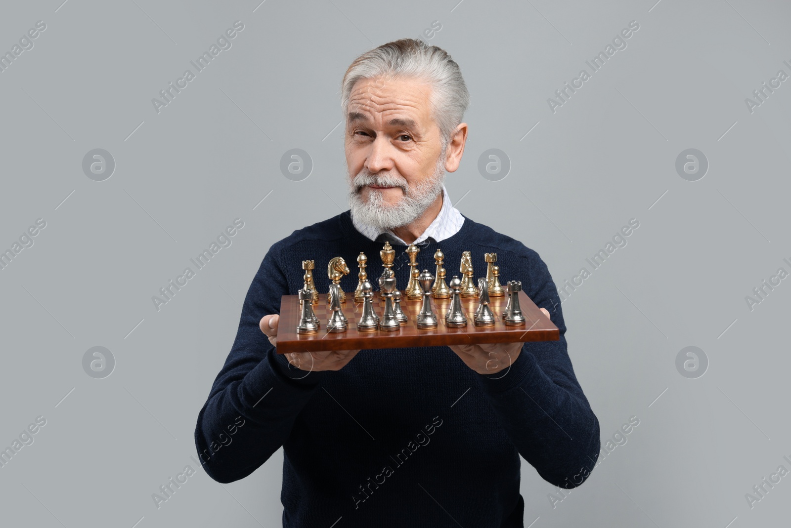 Photo of Man with chessboard and game pieces on light gray background