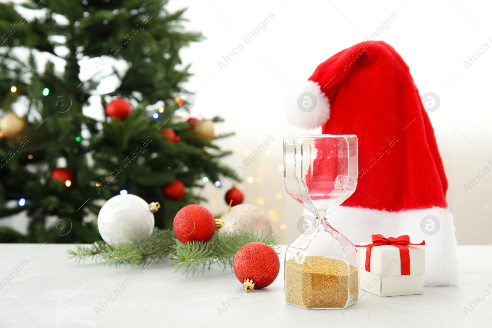 Photo of Hourglass with Santa hat and decor on table. Christmas countdown