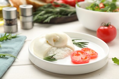 Photo of Delicious burrata cheese with rosemary and tomato on white wooden table