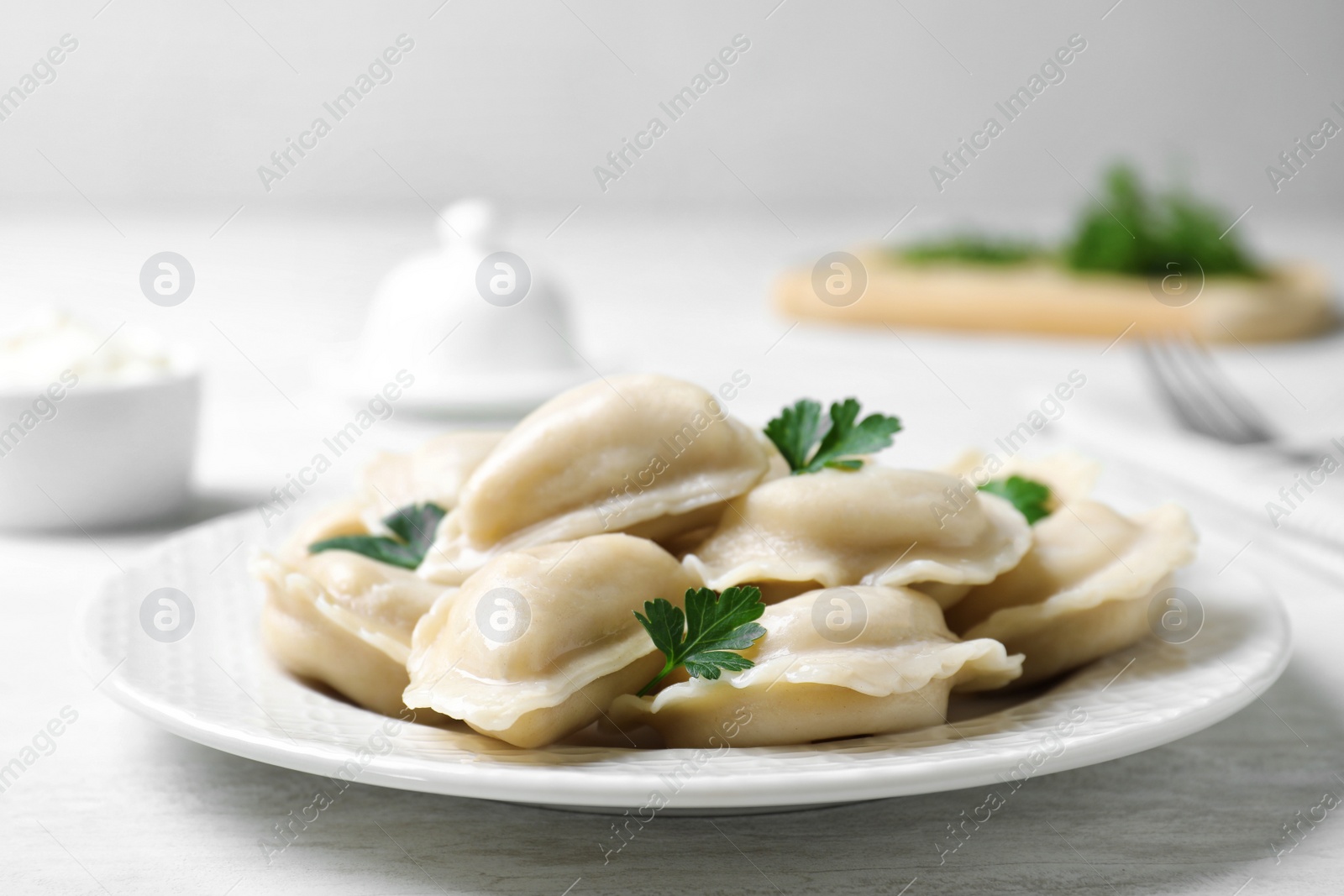 Photo of Plate of tasty dumplings served with parsley on table