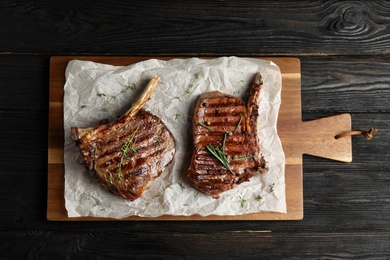 Photo of Board with grilled meat on wooden table, top view