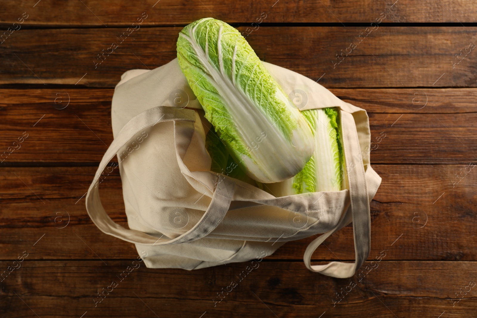 Photo of Textile eco bag with fresh ripe Chinese cabbages on wooden table, top view