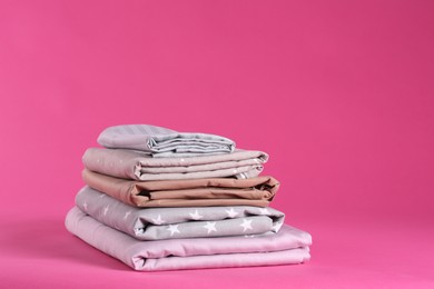 Photo of Stack of clean bed sheets on pink background