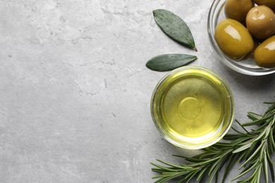 Photo of Cooking oil in bowl, olives and rosemary on light gray textured table, flat lay. Space for text