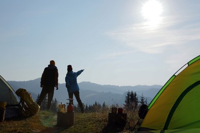 Photo of Couple enjoying beautiful mountain landscape near camping tents, back view