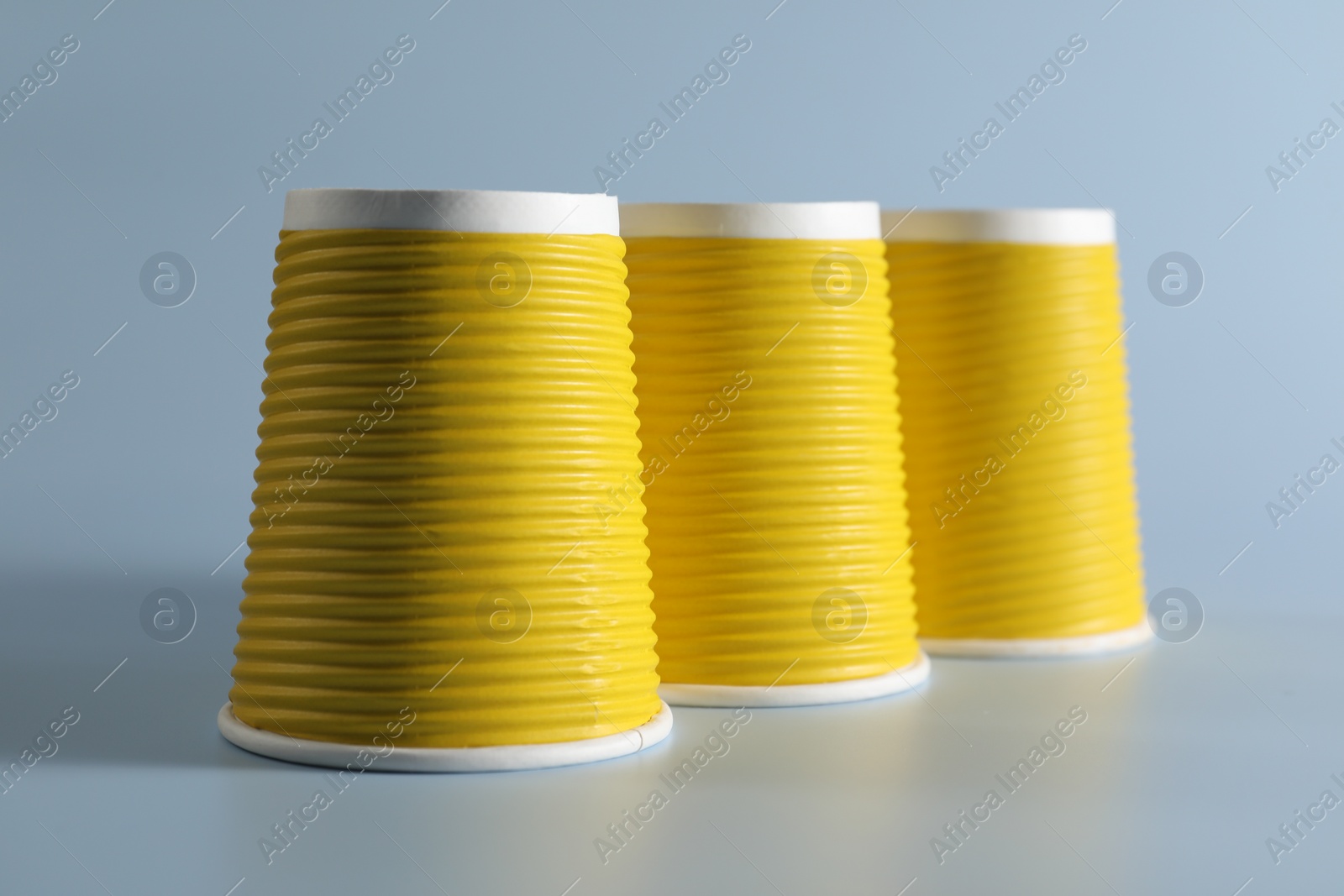 Photo of Shell game. Three yellow cups on light blue background
