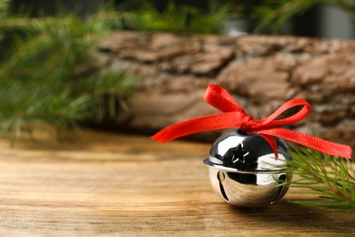 Shiny silver sleigh bell on wooden table. Space for text