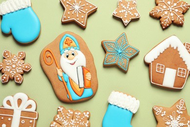 Tasty gingerbread cookies on light green background, flat lay. St. Nicholas Day celebration