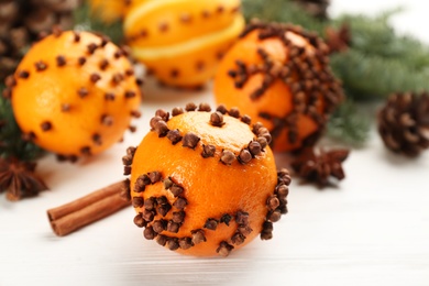 Photo of Pomander balls made of fresh tangerines with cloves on white wooden table. Christmas atmosphere