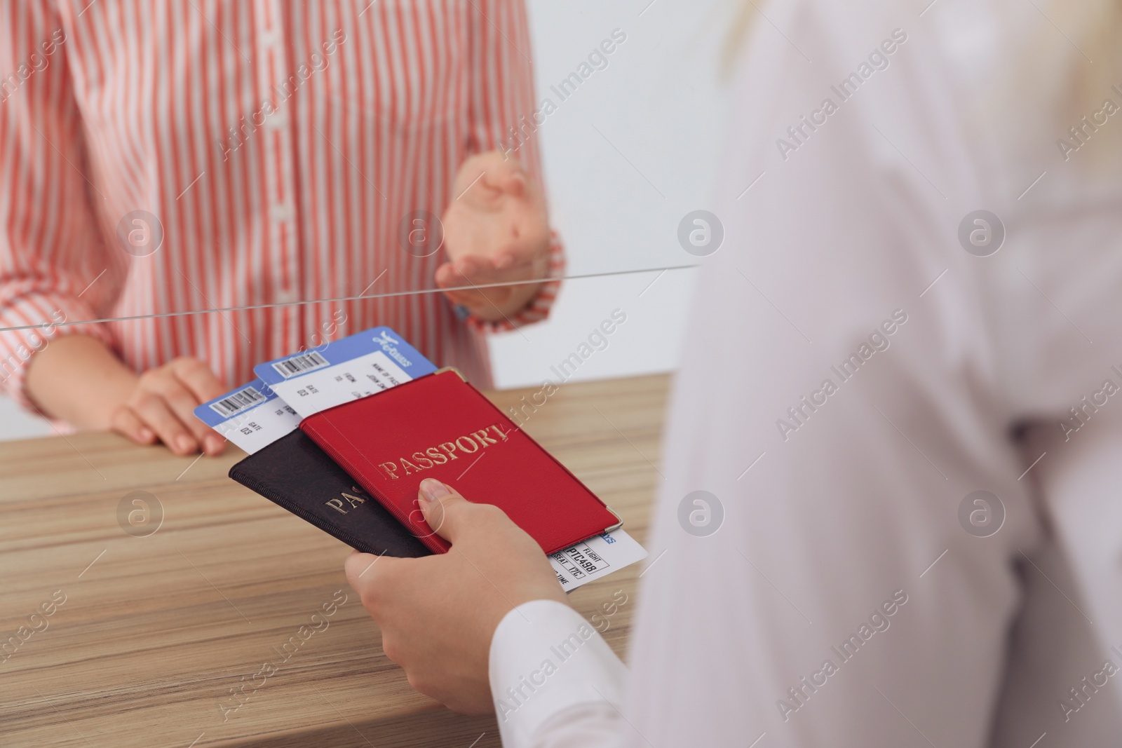 Photo of Agent giving passports with tickets to client at check-in desk in airport, closeup