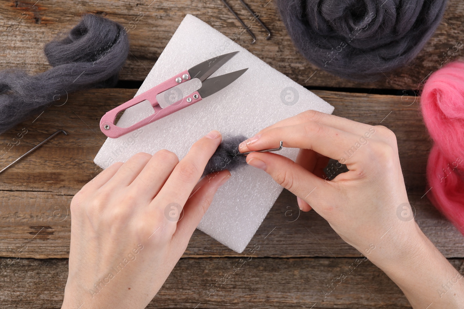 Photo of Woman felting from wool at wooden table, top view