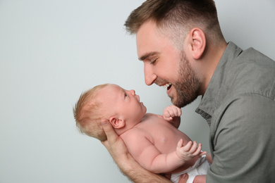 Father with his newborn son on light grey background