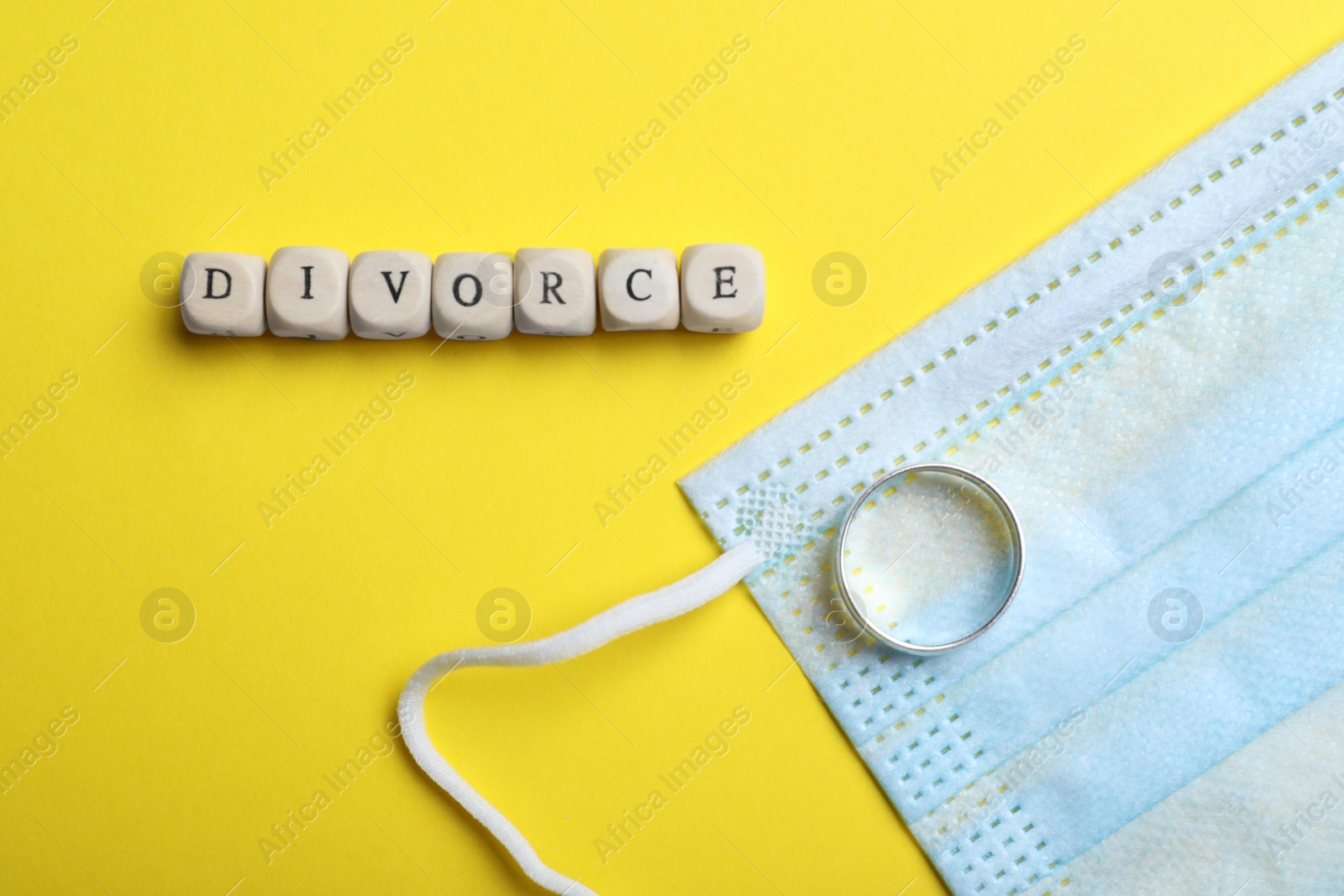 Photo of Flat lay composition with protective mask and wedding ring on yellow background. Divorce during coronavirus quarantine