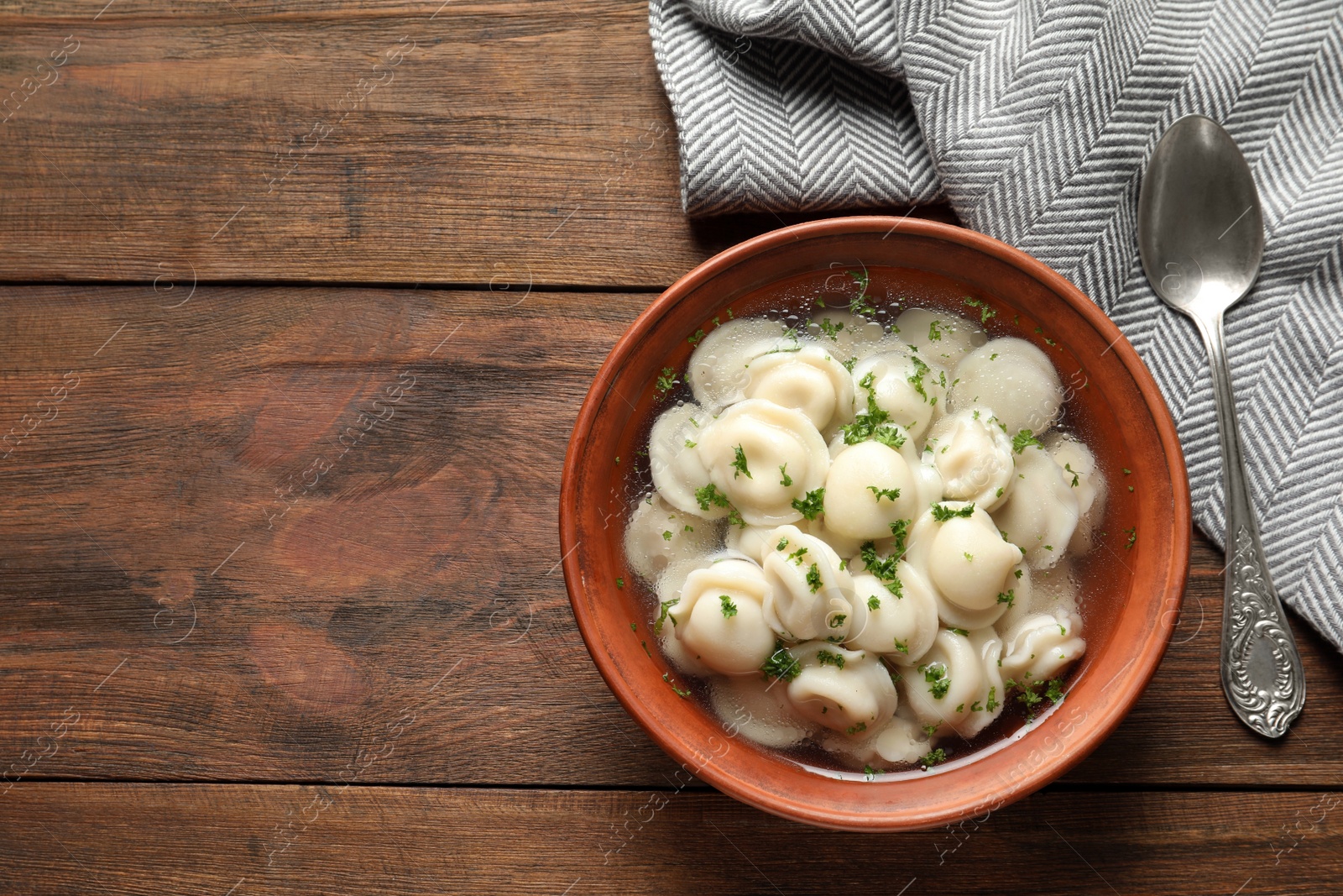 Photo of Bowl of tasty dumplings served on wooden table, top view. Space for text