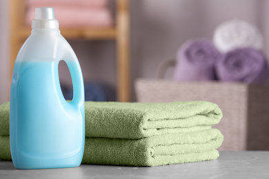 Folded clean towels and detergent on table in bathroom