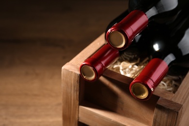 Wooden crate with bottles of wine on table. Space for text