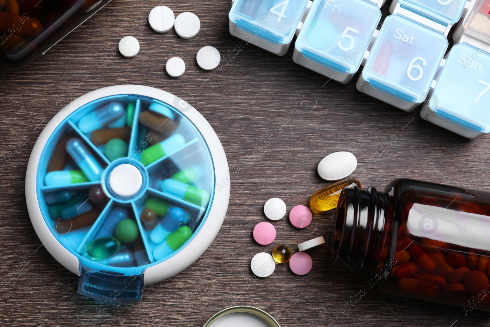 Photo of Pill boxes with medicaments on wooden table, flat lay