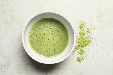 Photo of Cup of fresh matcha tea and green powder on light grey table, top view