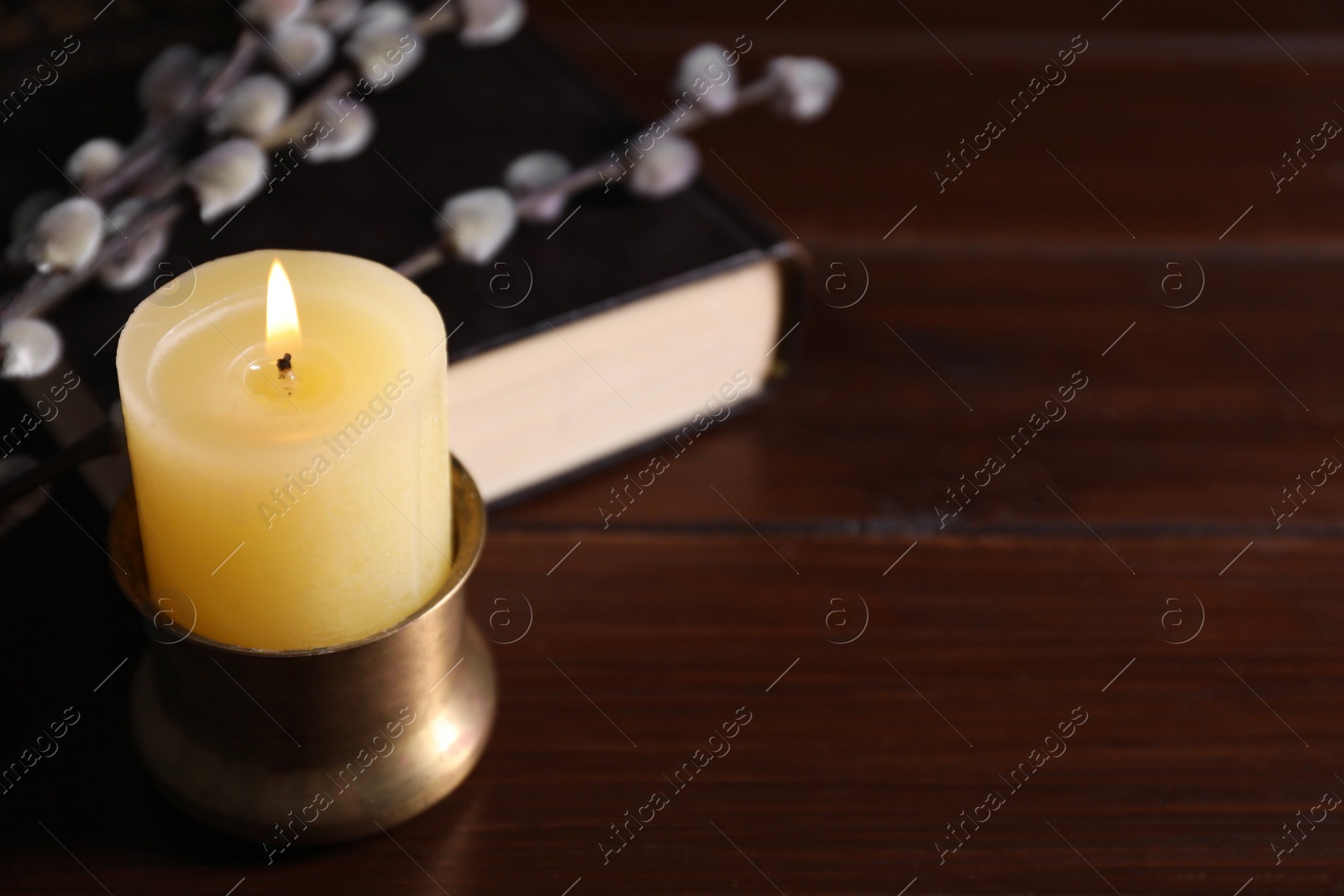 Photo of Burning candle on wooden table, closeup. Space for text