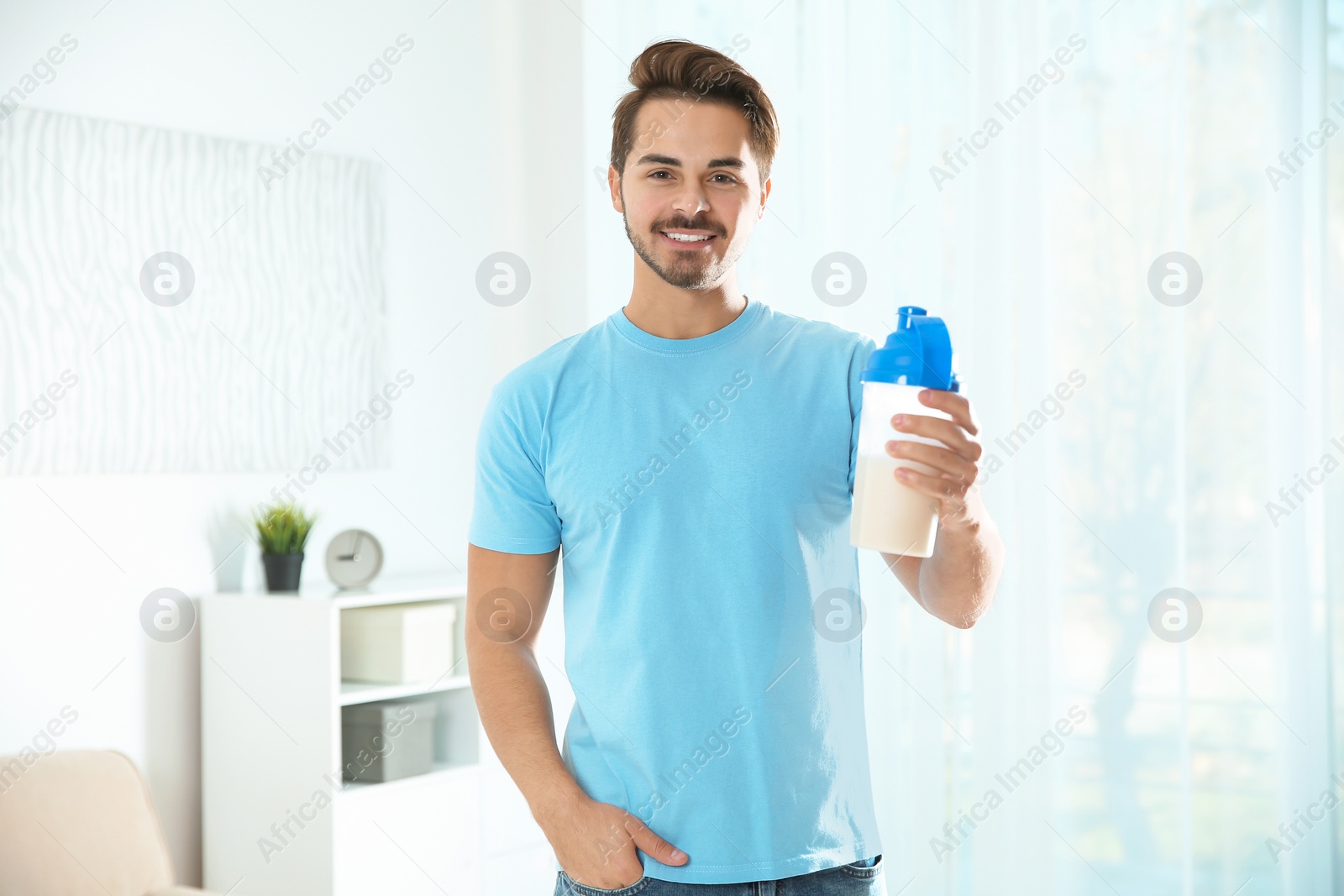 Photo of Young man with bottle of protein shake at home