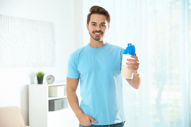 Young man with bottle of protein shake at home