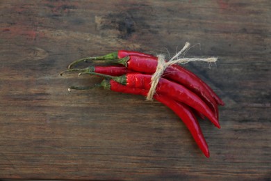 Fresh ripe chili peppers on wooden table, flat lay