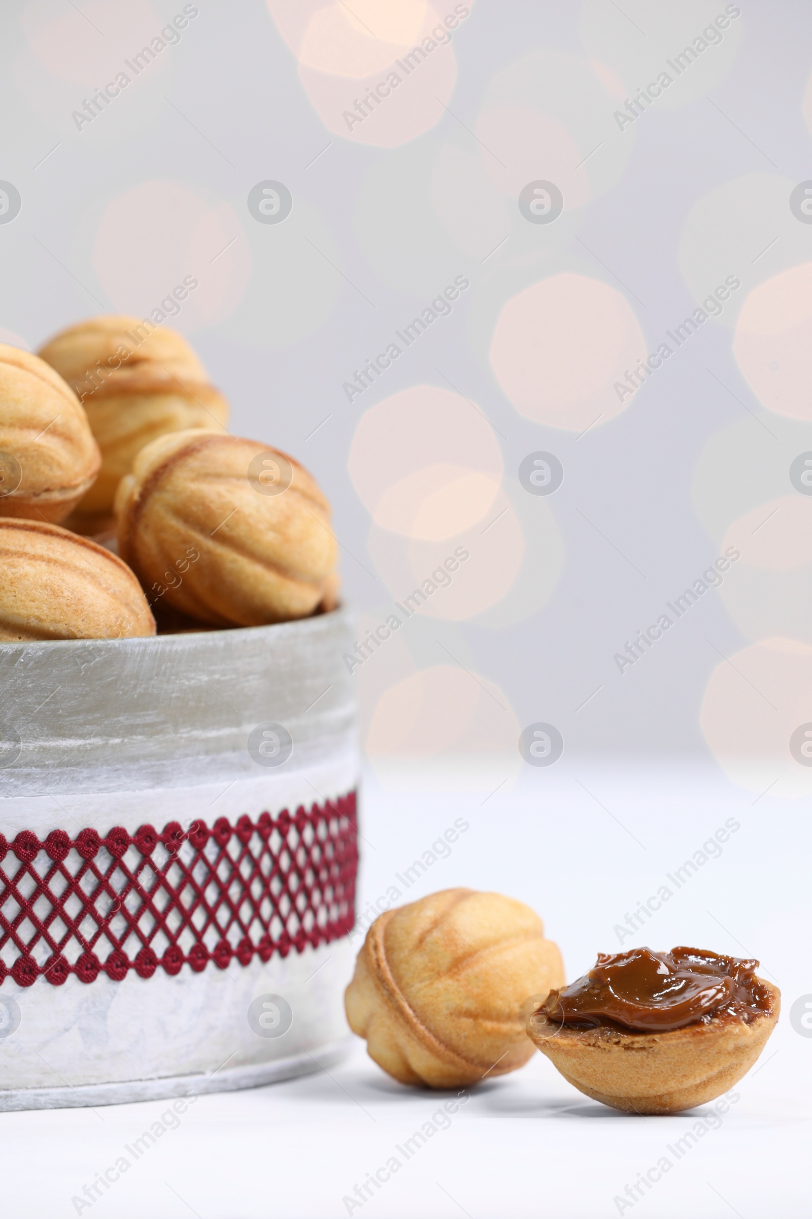 Photo of Homemade walnut shaped cookies with boiled condensed milk on white table, closeup. Bokeh effect