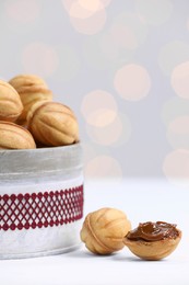 Photo of Homemade walnut shaped cookies with boiled condensed milk on white table, closeup. Bokeh effect