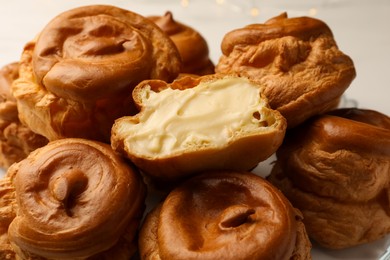 Photo of Delicious profiteroles with cream filling inside on white background, closeup