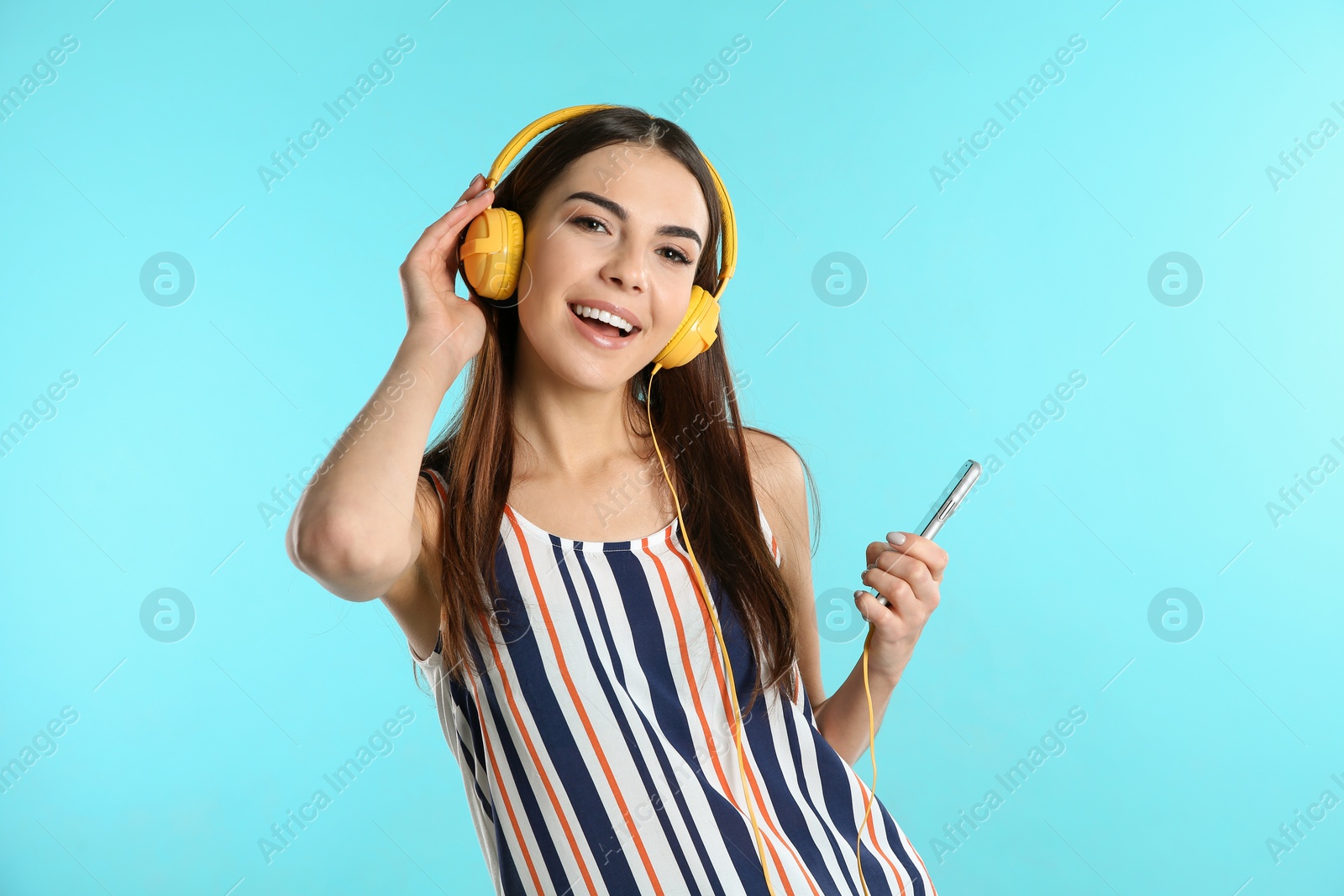 Photo of Beautiful young woman listening to music with headphones on color background