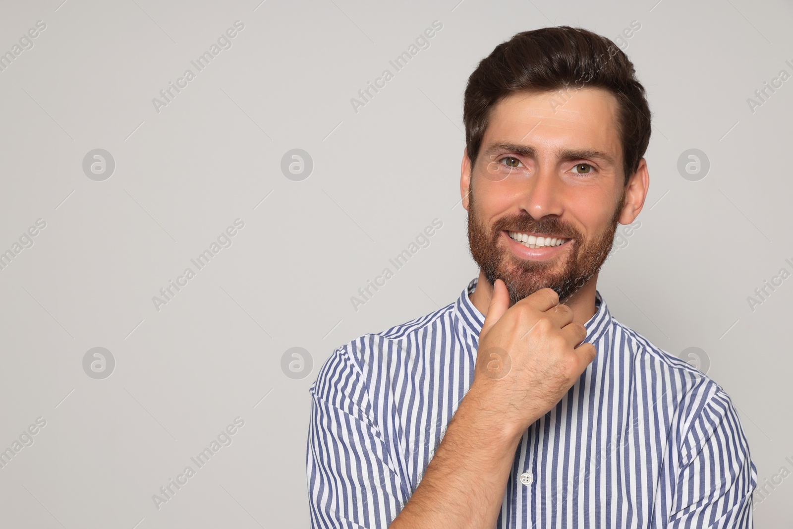 Photo of Portrait of smiling bearded man on grey background. Space for text